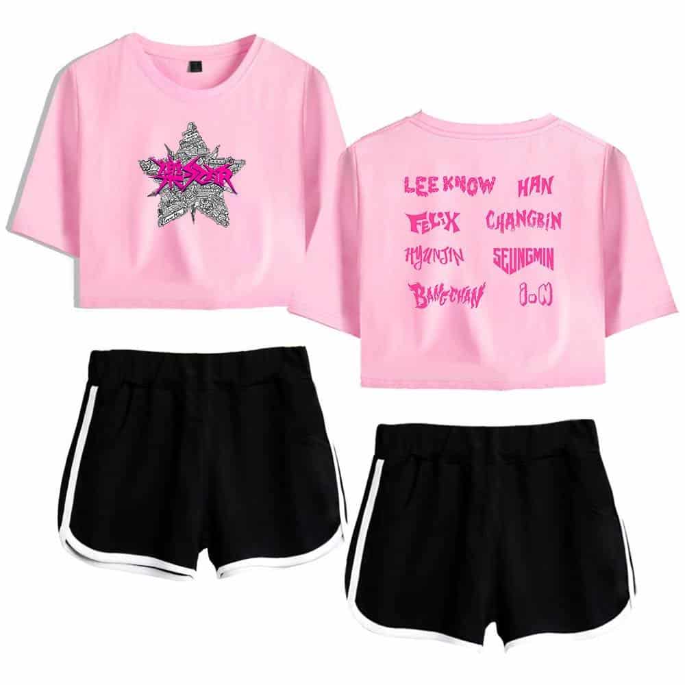 Kpop merch pink crop top with graphic design and black shorts with white stripe detailing.